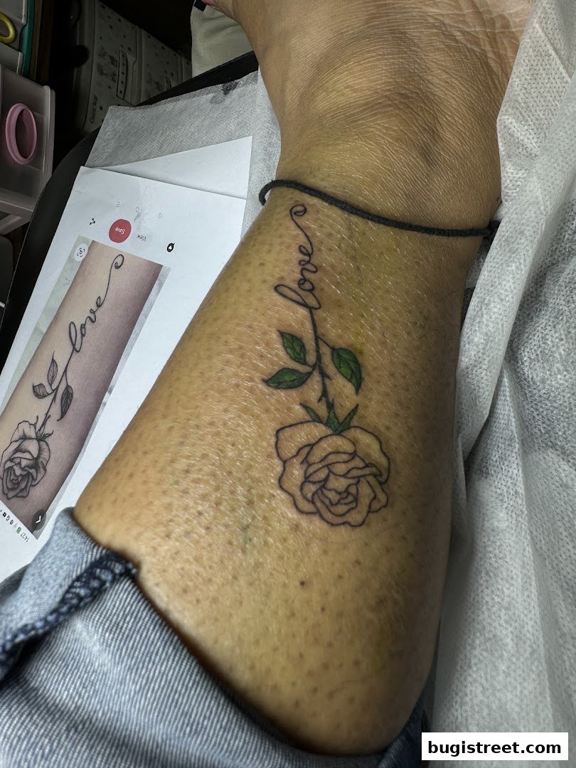 A person's leg with a new tattoo of a rose and the word 'love'.