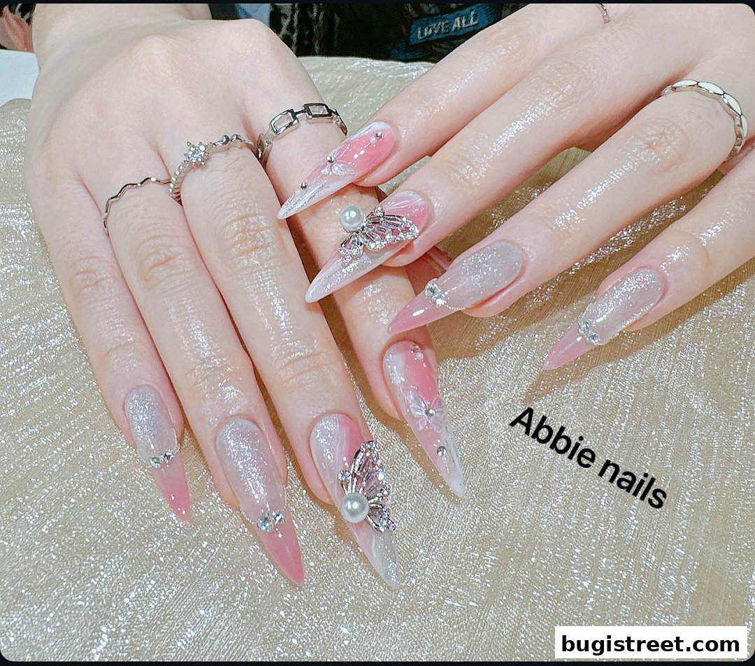 Close-up of hands with elaborately decorated long nails featuring pink, white, and glitter accents.