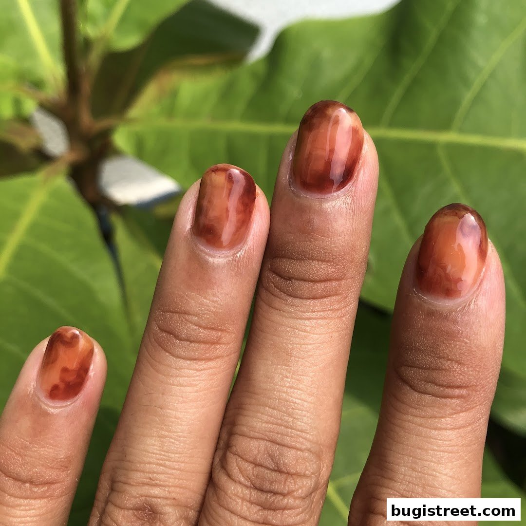 Close-up of a hand with beautifully manicured nails featuring a unique brown marble design.