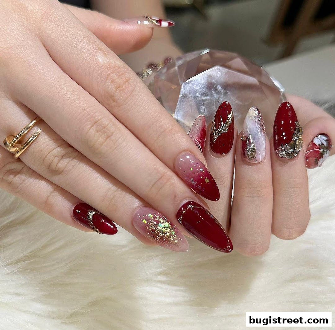 Close-up of hands with elaborately decorated nails in red and gold.