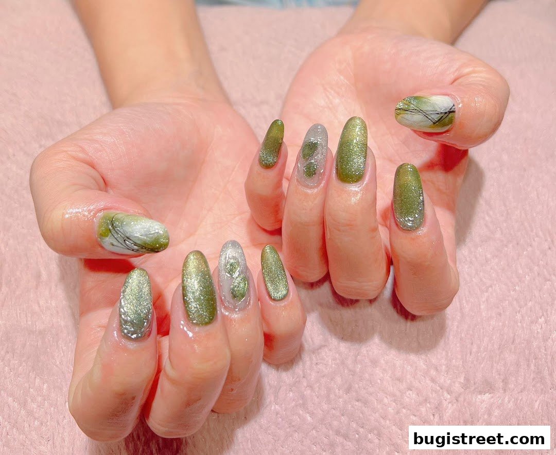 A close-up shot of hands with beautifully designed green and silver ombre nails.