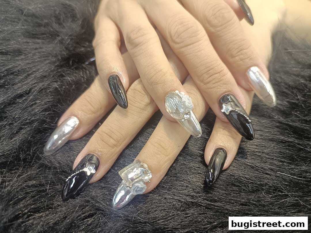 Close-up of hands with glamorous black and silver chrome nails with intricate embellishments.