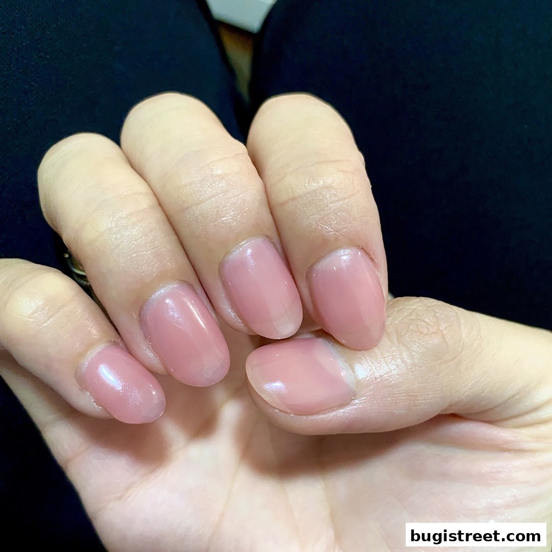 Close-up of a hand with neatly manicured nails painted in a soft pink shade.