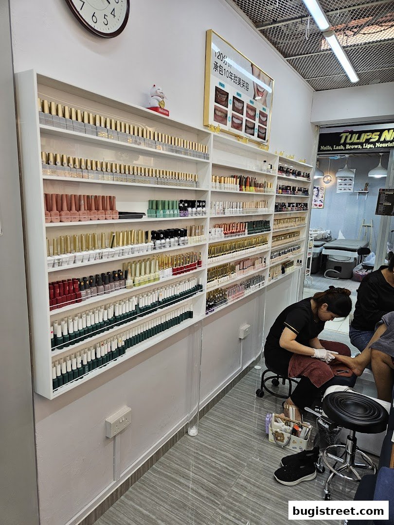Nail salon interior with shelves of nail polish and technicians performing services.