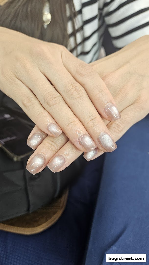 Close-up of a person's hands with elegant, shimmering nude-colored nails.