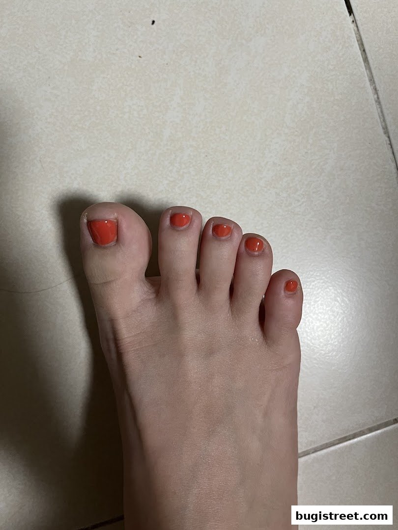 A close-up view of a person's foot with freshly painted orange toenails.