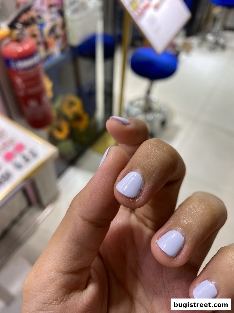 A close-up of a hand with light purple nail polish applied at Angel Nail Lashes Studio.