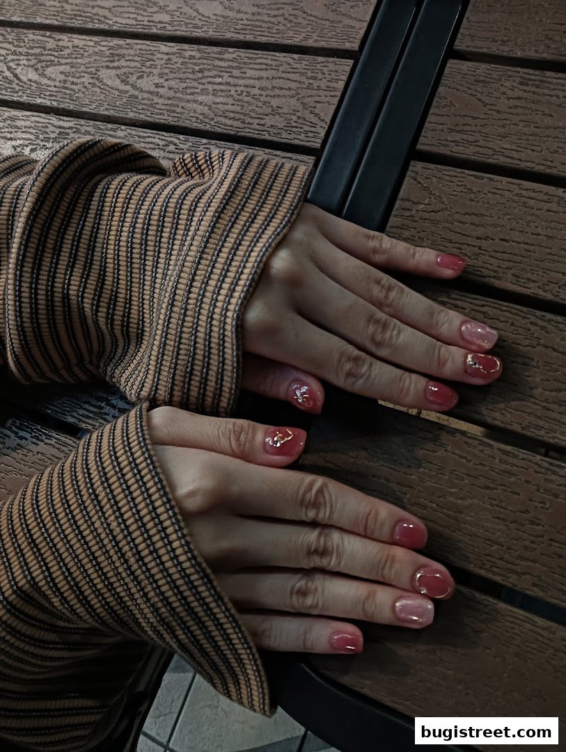 Close-up of hands with beautifully manicured nails featuring a mix of pink and glitter polish.