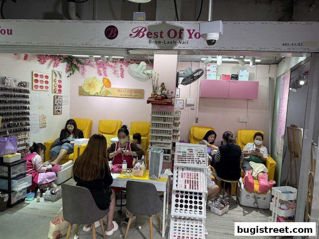 Interior of a beauty salon with customers receiving nail and brow services.
