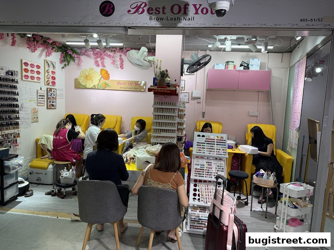 Interior of a beauty salon with customers receiving nail services and displays of nail polish.