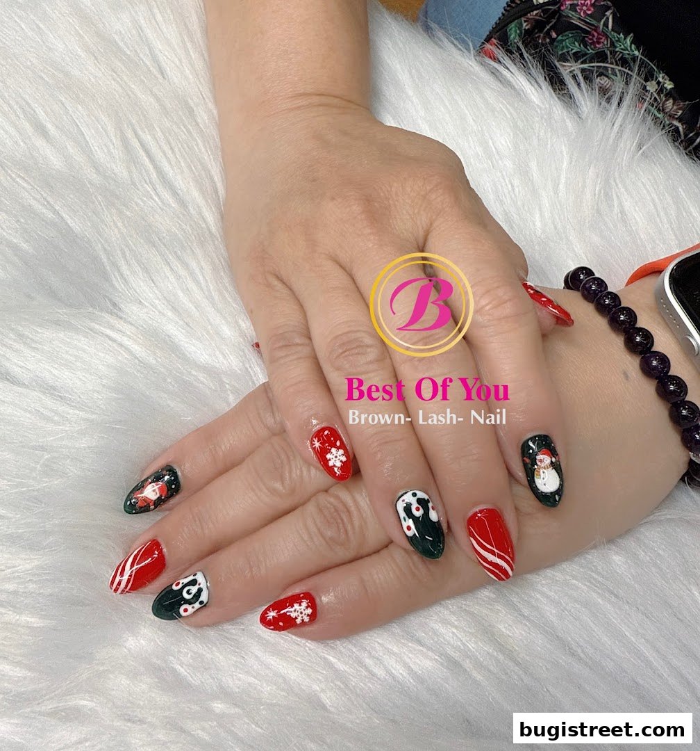 A close-up of hands with festive Christmas-themed nail art, including Santa, snowmen, and snowflakes.