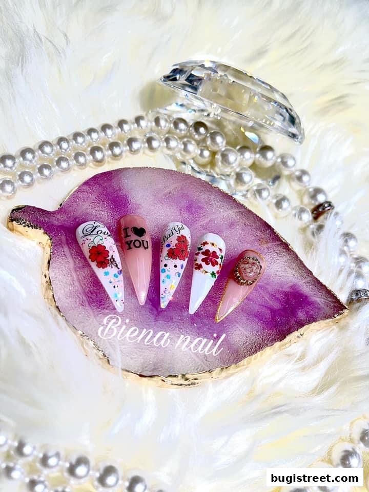A display of five elaborately designed stiletto nails with floral and text accents.