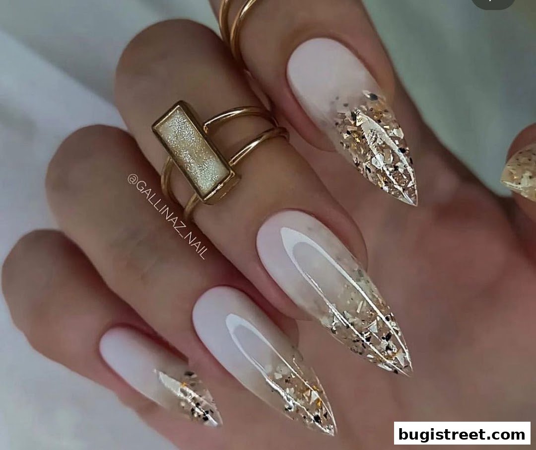 Close-up of a hand with elegant stiletto nails featuring a French tip and glitter accents.