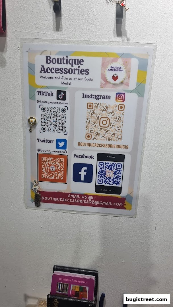 A sign displays social media handles and QR codes for Boutique Accessories.