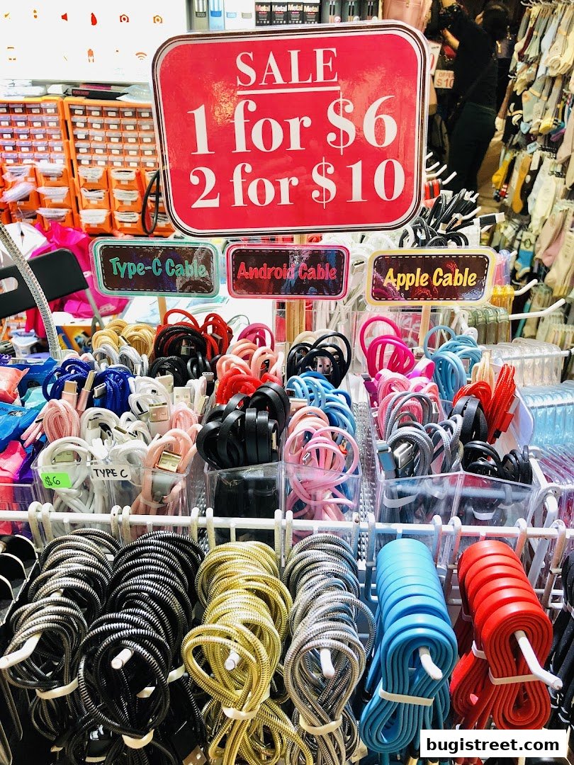 A display of various charging cables, including Type-C, Android, and Apple cables, with a sale sign.