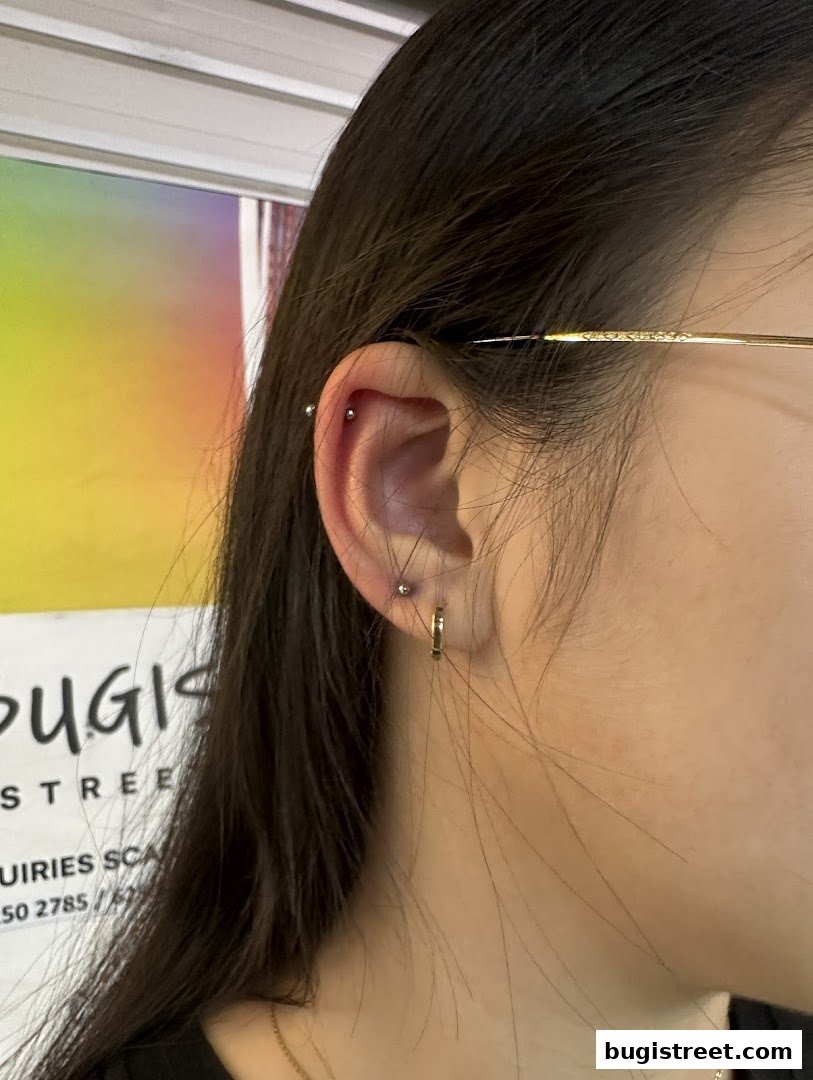 Close-up of a woman's ear with multiple piercings, showcasing stylish jewelry.