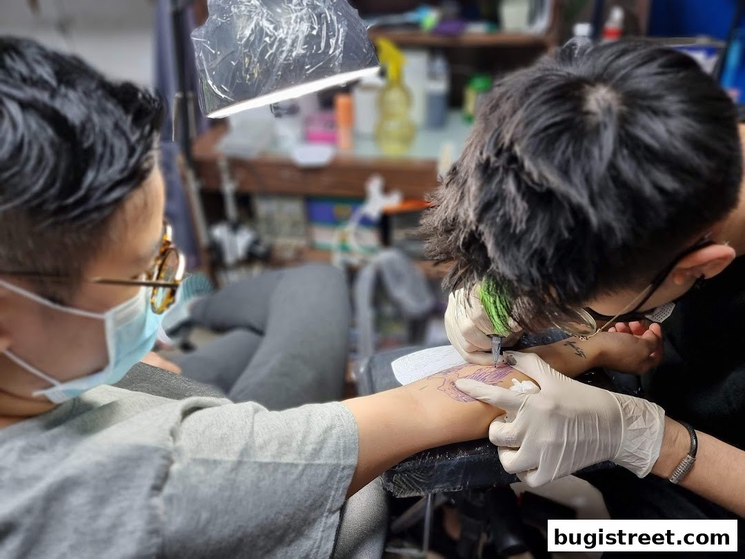 A tattoo artist is in the process of tattooing a client's arm in a studio.