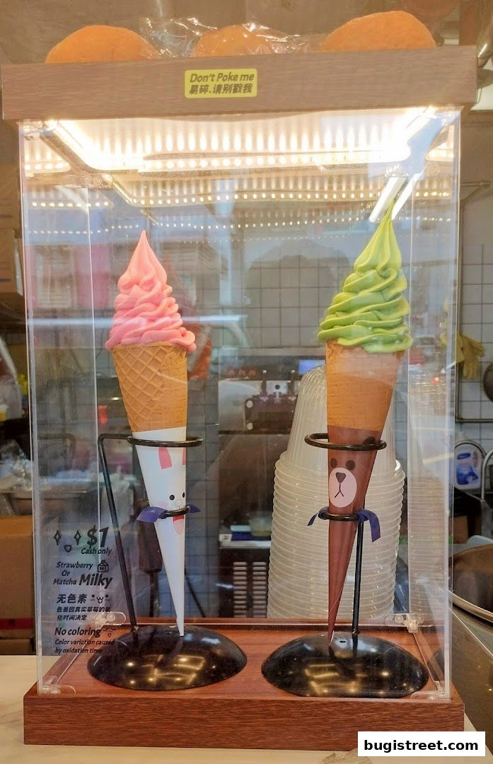 Two soft-serve ice creams, one strawberry and one matcha, displayed in cones with cute animal designs.
