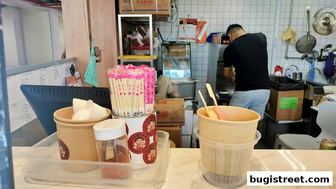 A chef prepares food behind the counter at Chanko Oden, with chopsticks and bowls in the foreground.
