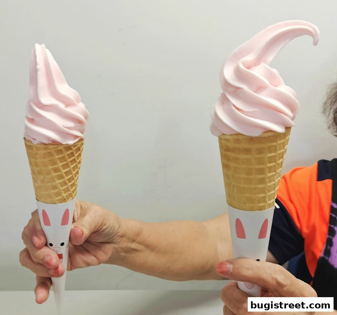 Two hands hold pink soft-serve ice cream cones with bunny-themed wrappers.
