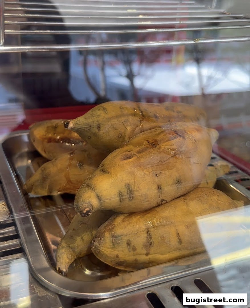A close-up shot of several baked sweet potatoes in a metal tray.