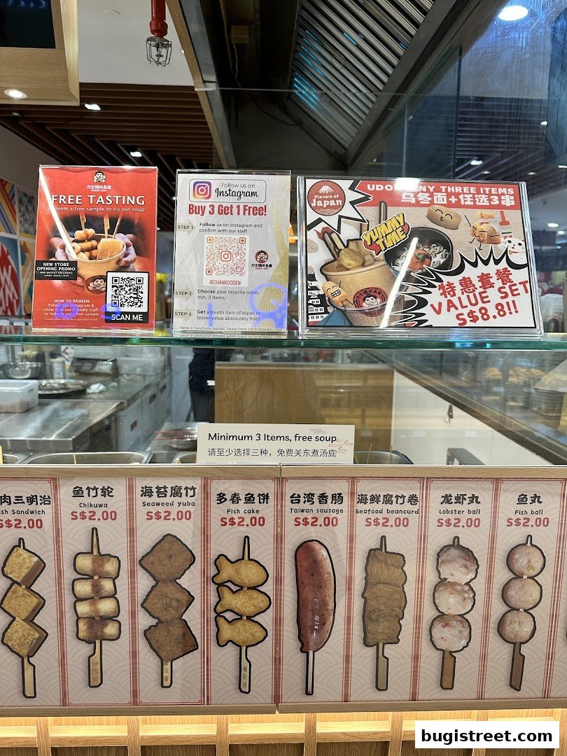 A display of various Oden skewers and promotional signs at a food stall.