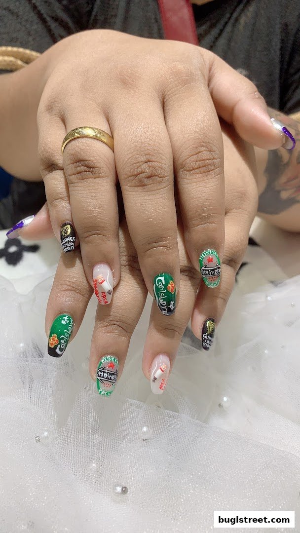 Close-up of hands with creative nail art featuring beer brand designs.