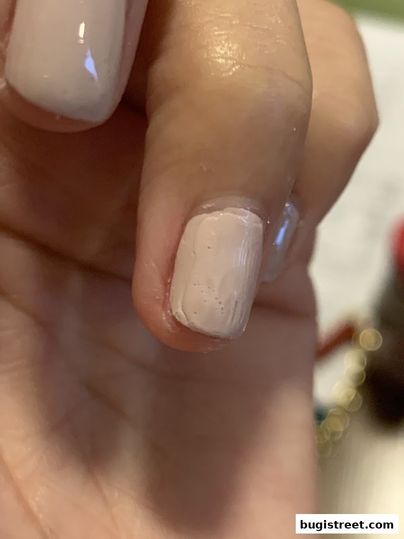Close-up of a hand with neatly painted light pink nails, showcasing a fresh manicure.