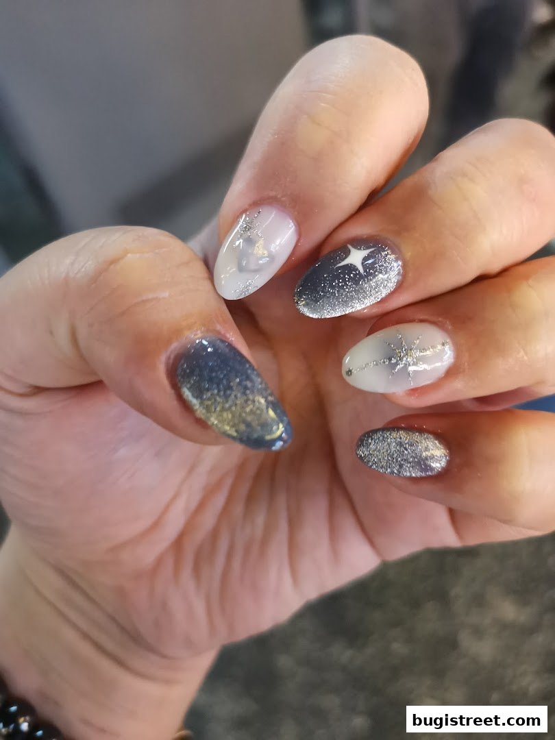 Close-up of a hand with beautifully designed nails featuring glitter and star accents.