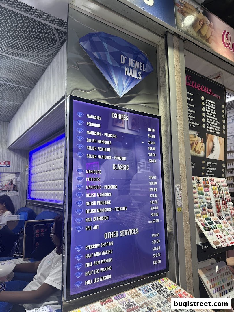 A digital menu board displays nail services and prices for D' Jewel Nails.