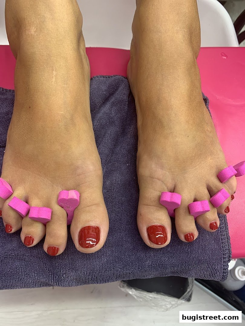 A close-up of feet with red nail polish and toe separators.