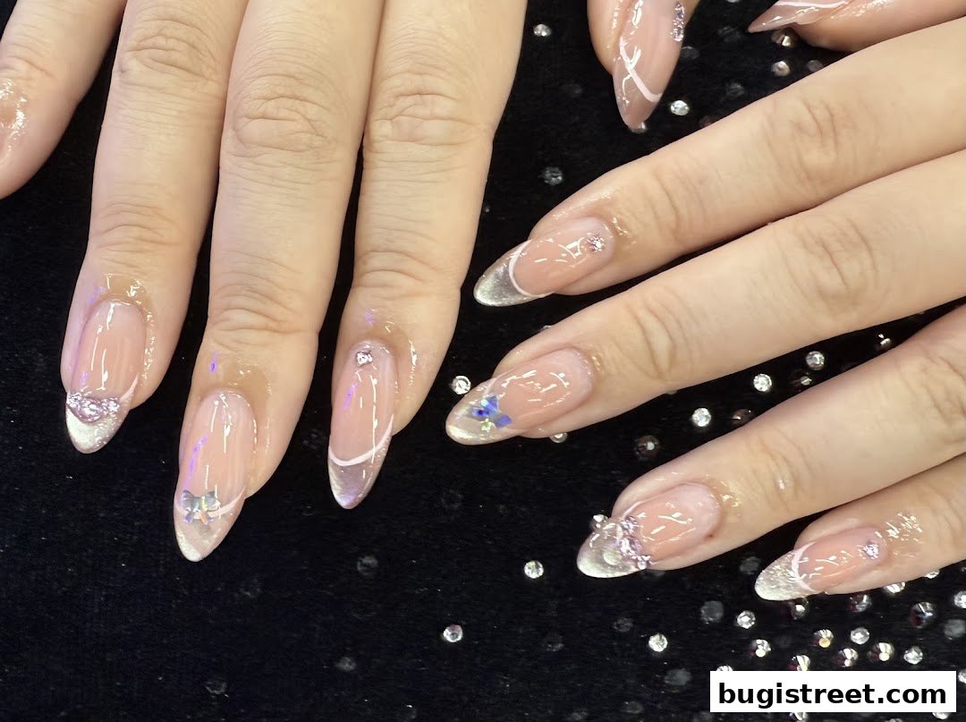 Close-up of hands with beautifully decorated French tip nails featuring gems and subtle designs.