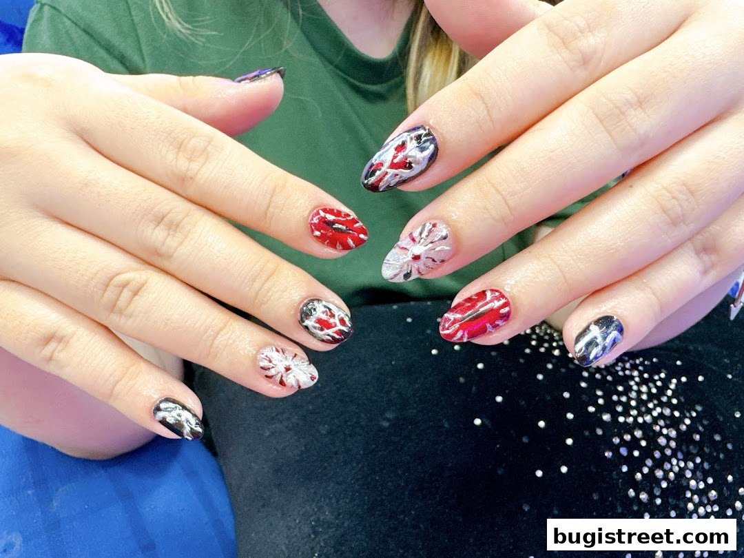 Close-up of hands with intricately designed nails featuring red, white, and black patterns.