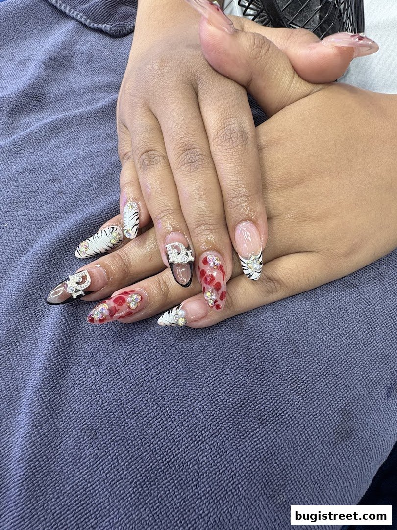 A close-up of hands with elaborately decorated long nails featuring various designs and embellishments.