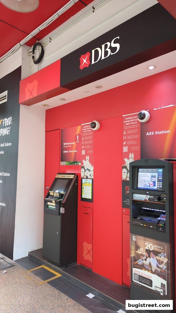 Exterior of a DBS ATM and AXS station with red branding and informational posters.
