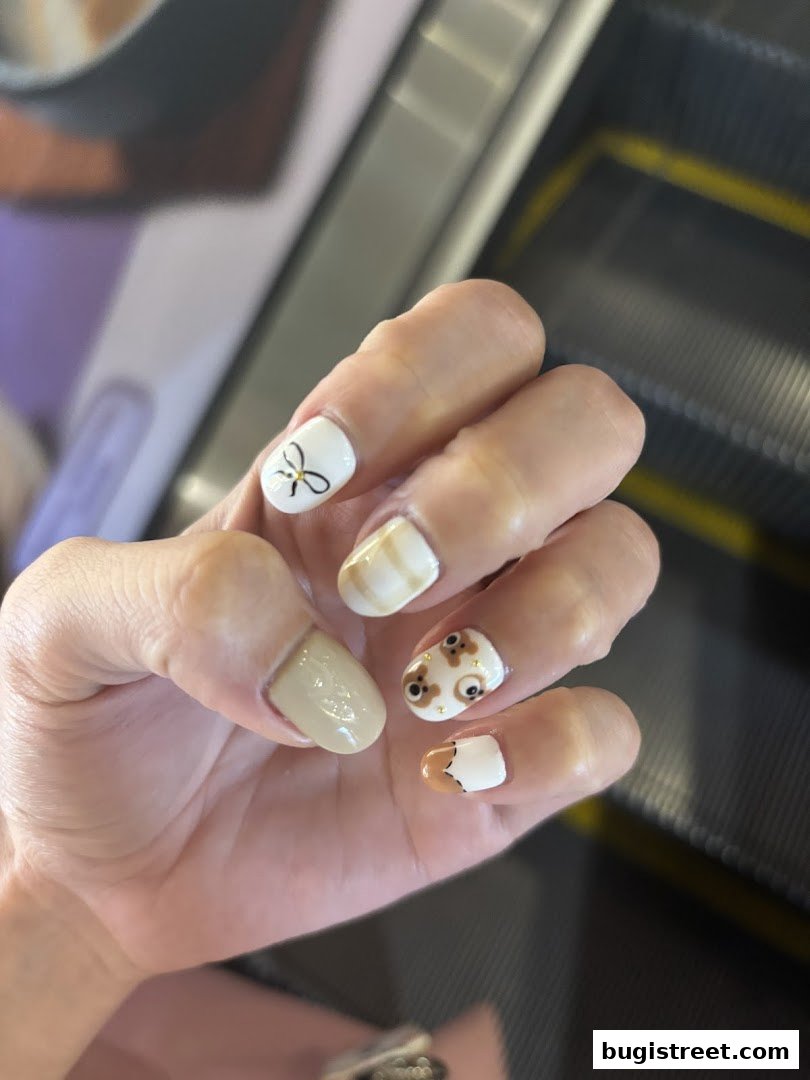 A close-up of a hand with intricately designed nails featuring cute animal and bow motifs.