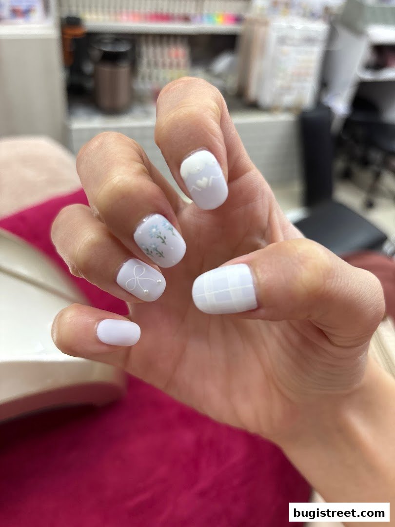 A close-up of a hand with beautifully decorated white and light purple nails.