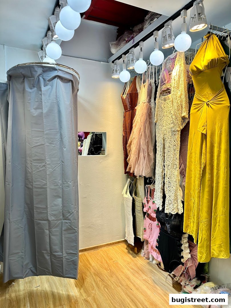 A fitting room and a rack of stylish dresses in a boutique.
