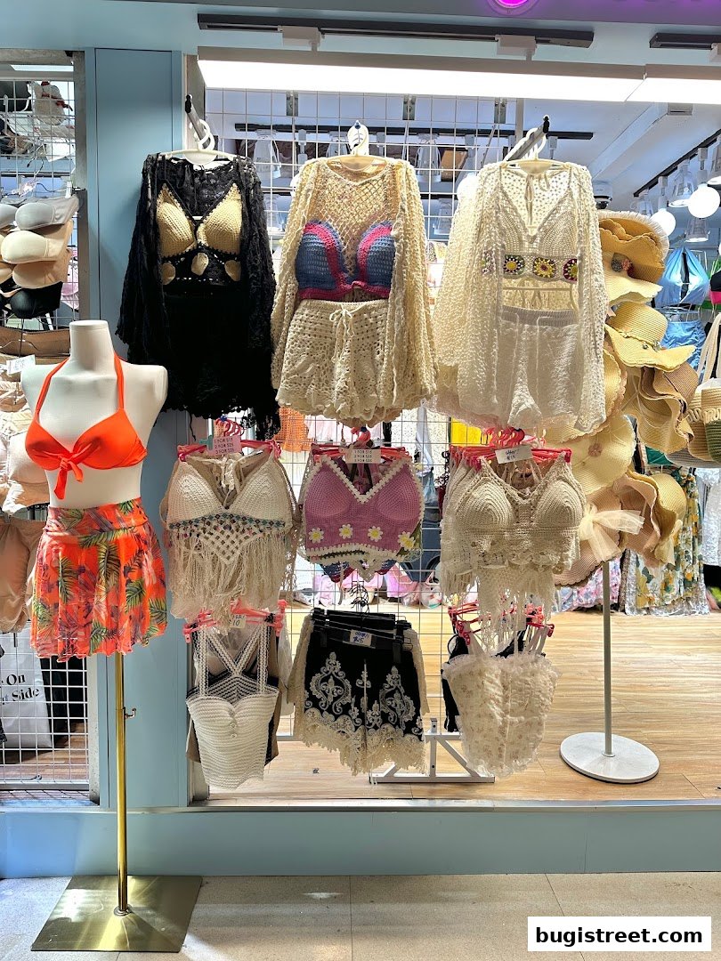 A display of women's summer clothing, including crochet tops, shorts, and swimwear.
