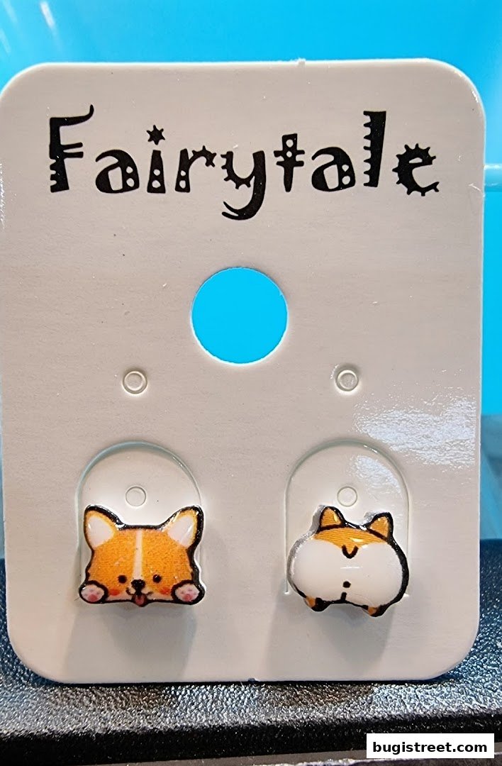 A pair of cute corgi-themed earrings displayed on a white card with the shop name 'Fairytale'.