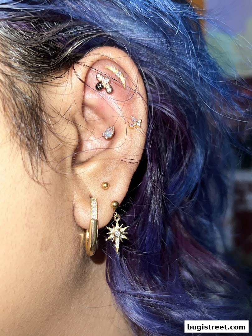 Close-up of a person's ear adorned with multiple stylish gold piercings and earrings.