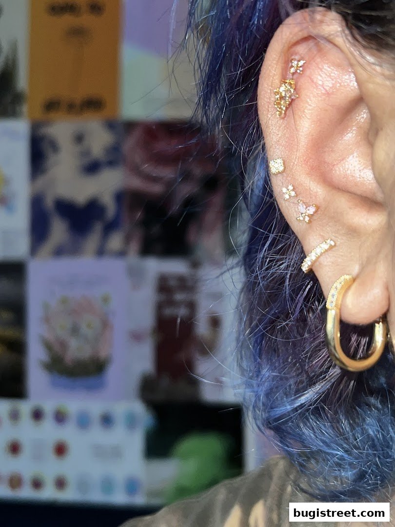 A close-up of an ear adorned with multiple delicate gold piercings and a hoop earring.