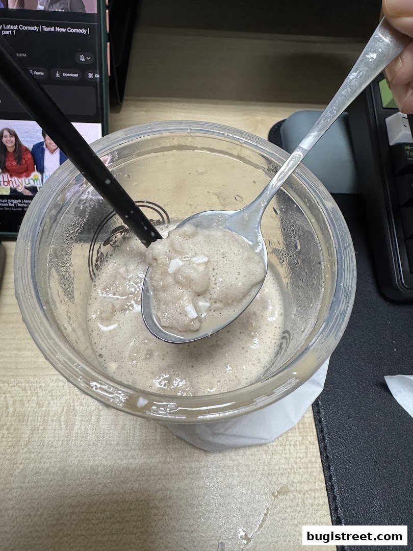A close-up of a creamy beverage with chunks, being scooped with a spoon.