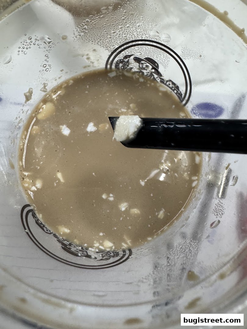 A close-up of a coffee drink with a straw and ice, showing condensation on the cup.