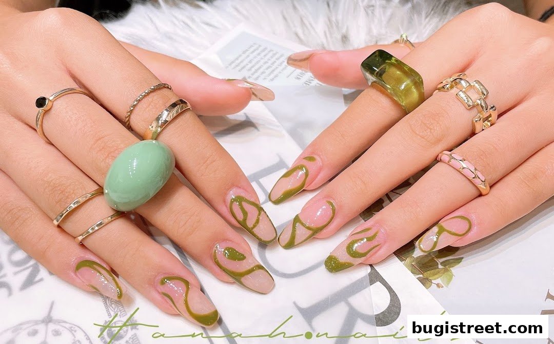 Close-up of hands with stylish green abstract nail art and rings.