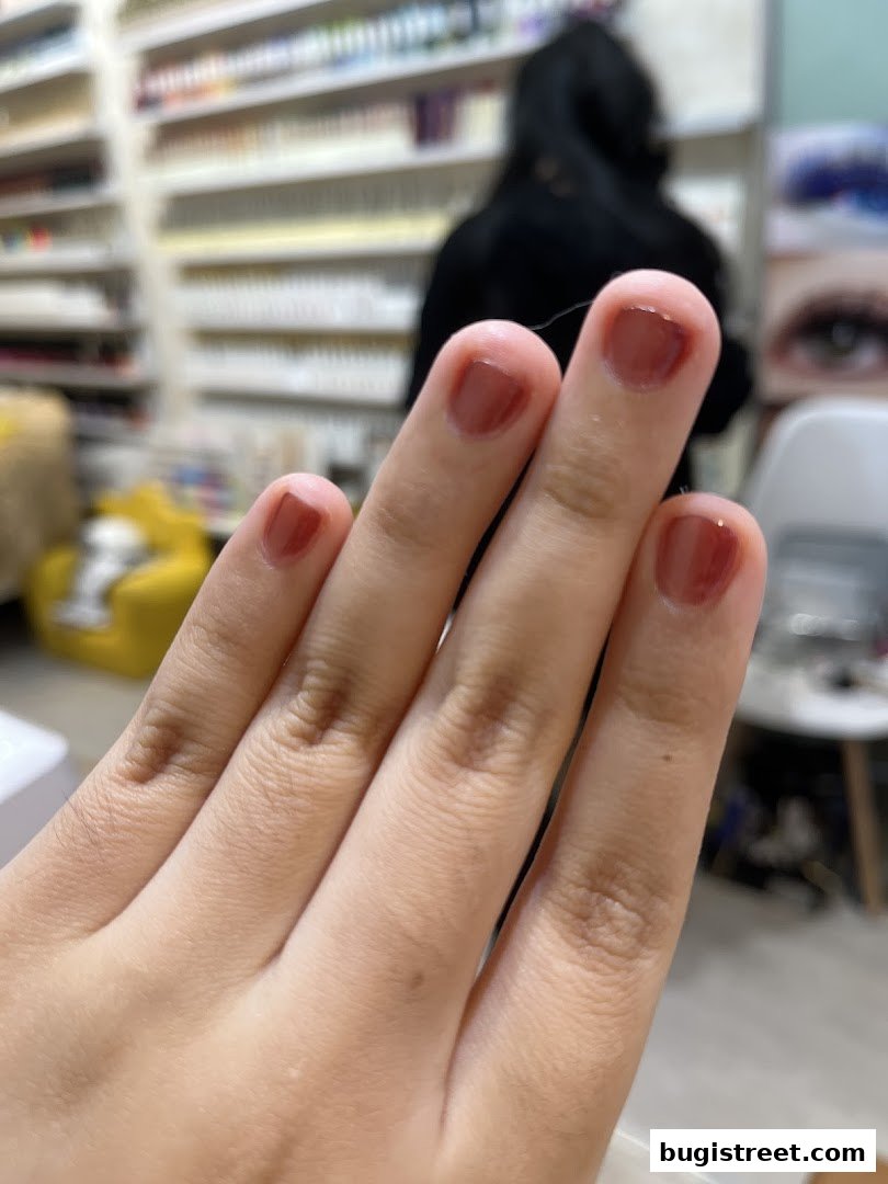 A close-up of a hand with freshly painted, glossy brown nails.