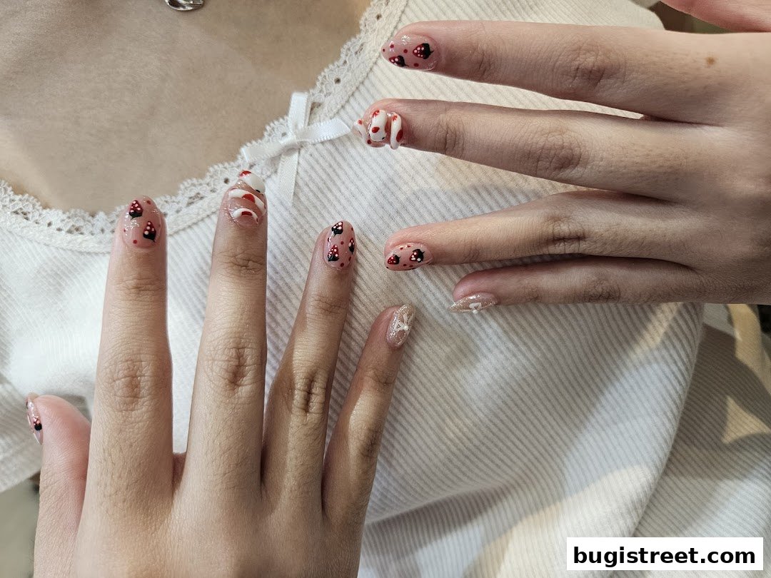 Close-up of hands with intricate nail art featuring cartoon characters and red and white swirls.