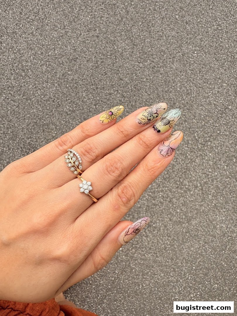 A hand with beautifully designed floral pattern nails and elegant rings.