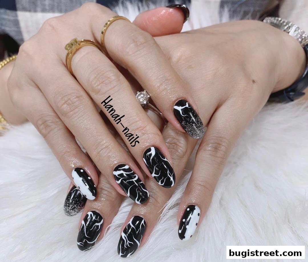 Close-up of hands with stylish black and white nail art and rings.