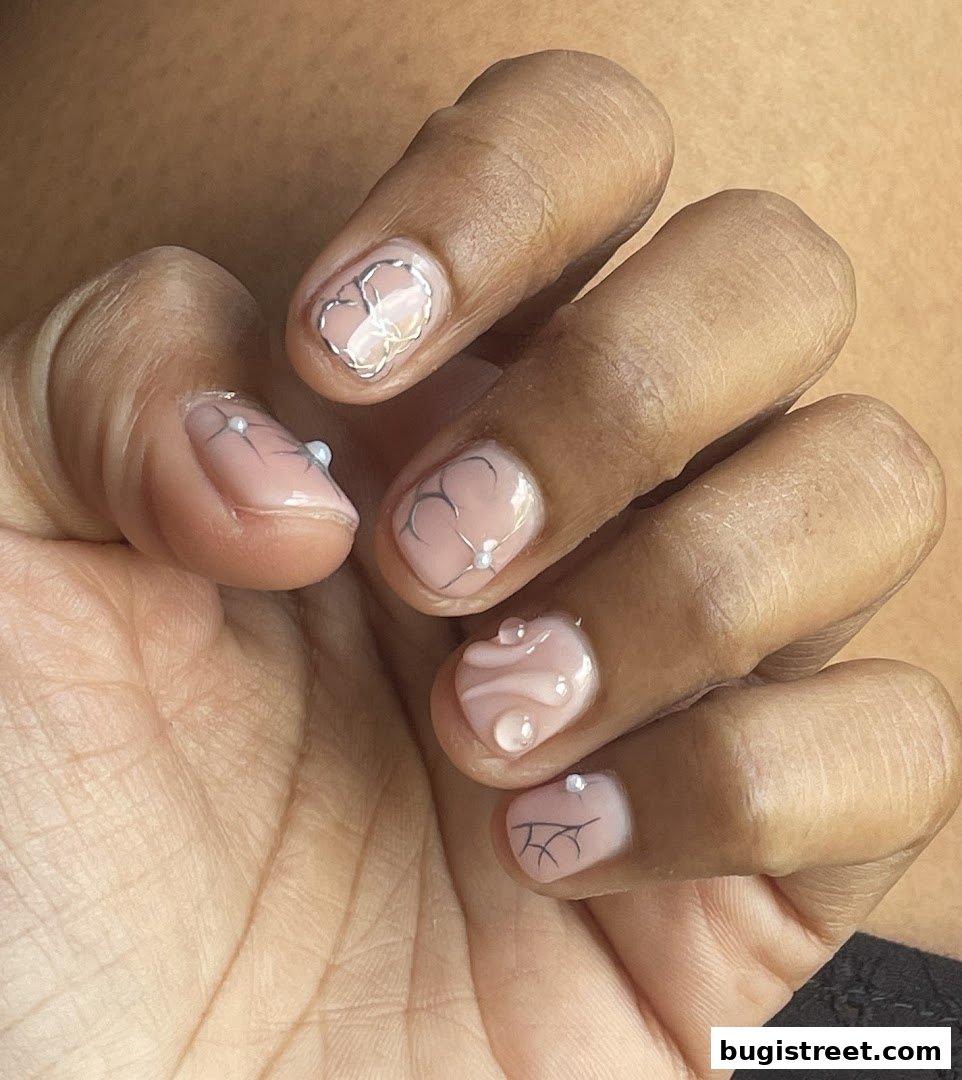 Close-up of a hand with delicate, artistic nail art featuring floral designs and small pearls.